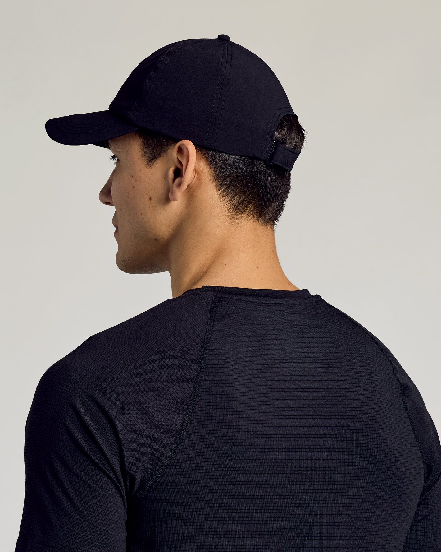 Black Active Running Cap on man, showcasing its sleek fit and design.
