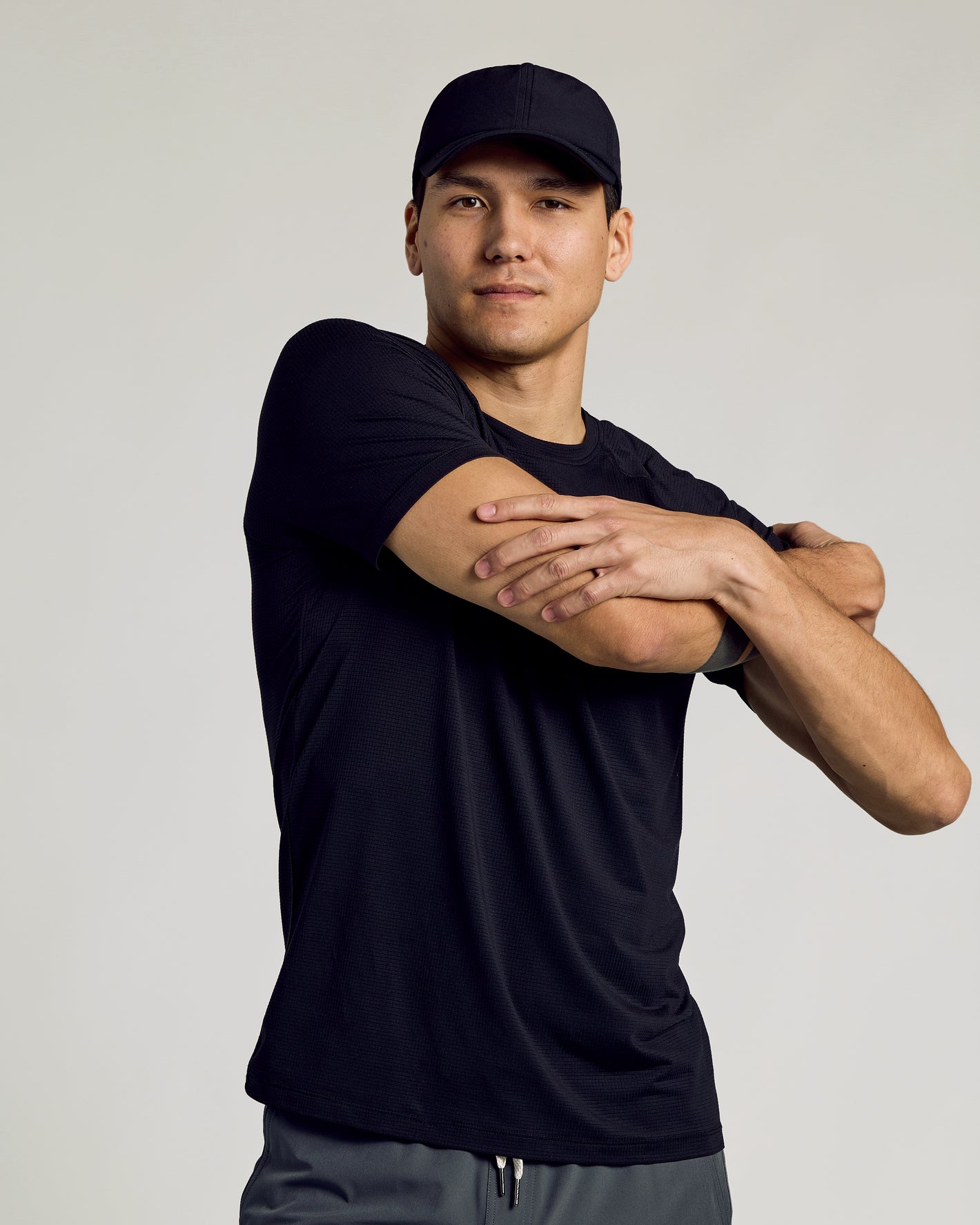 Young man wearing Black Active Running Cap performing stretch.