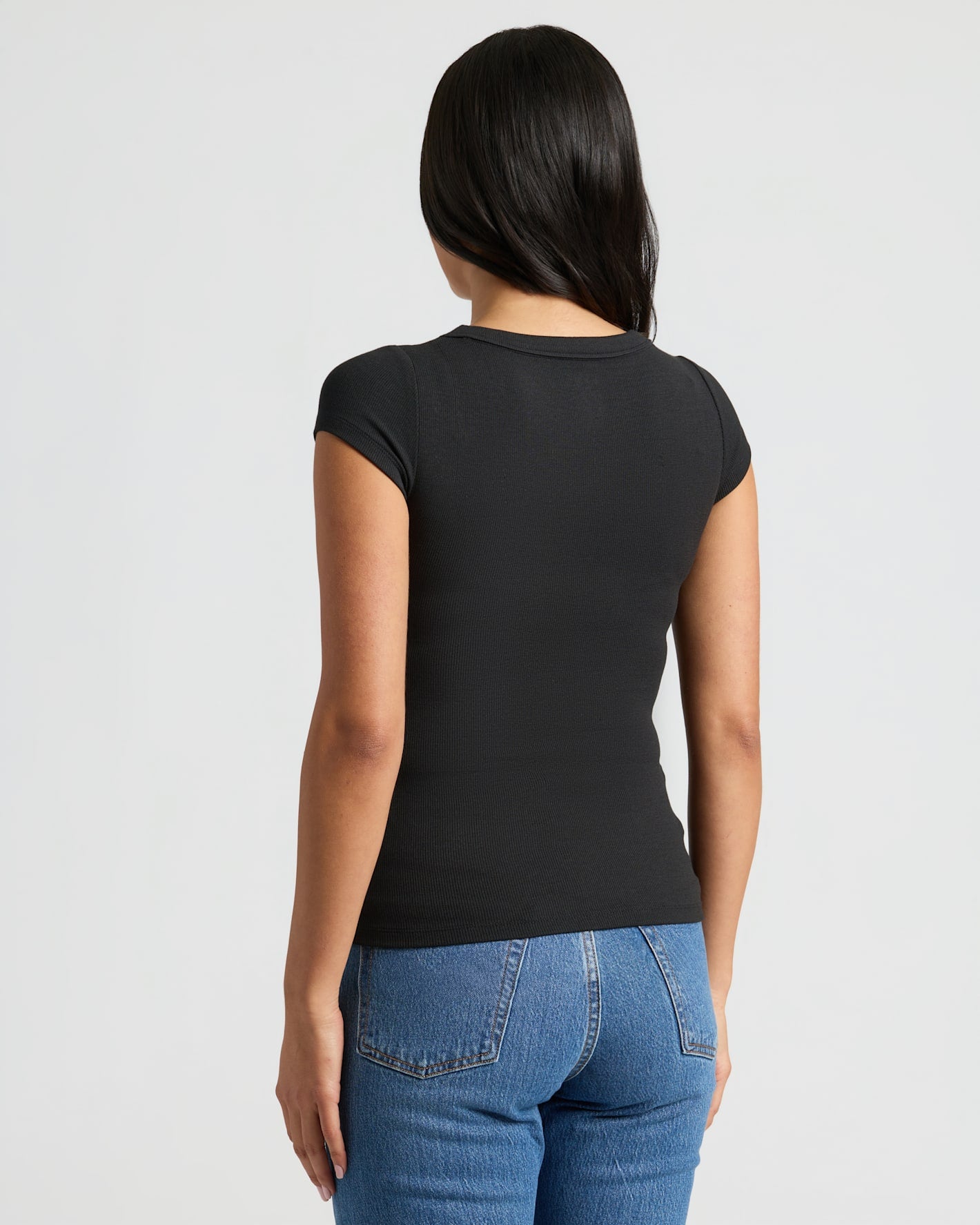 Person wearing Womens Black Ribbed U-Neck Tee with blue jeans.