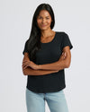Woman wearing a black t-shirt and light blue jeans against a white background