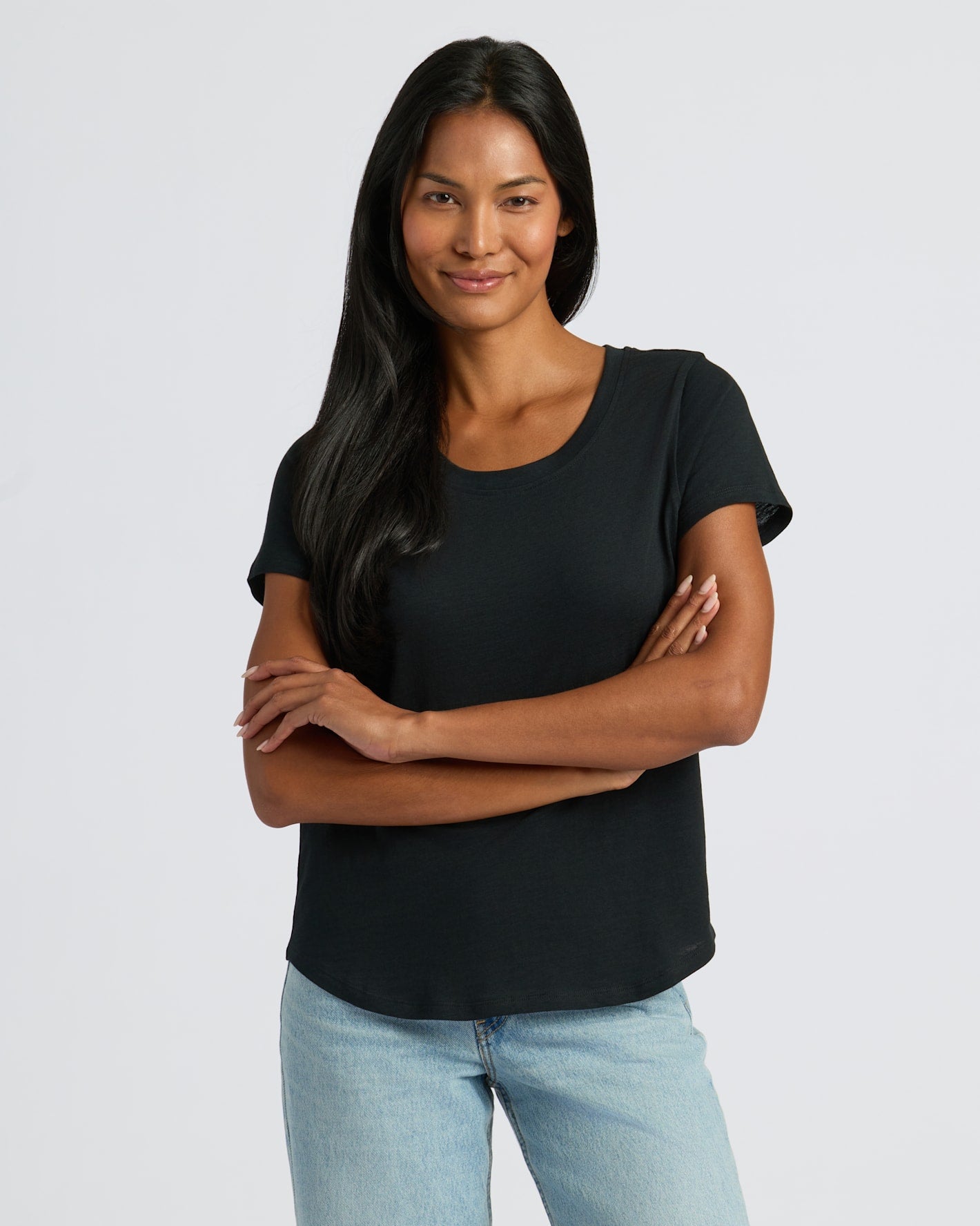 Woman wearing a black t-shirt and light blue jeans against a white background
