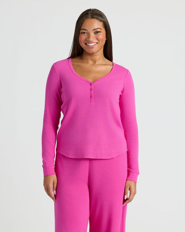 Woman wearing a pink long-sleeve top and pants on a white background