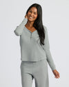 Woman wearing a gray long-sleeve top and pants on a white background