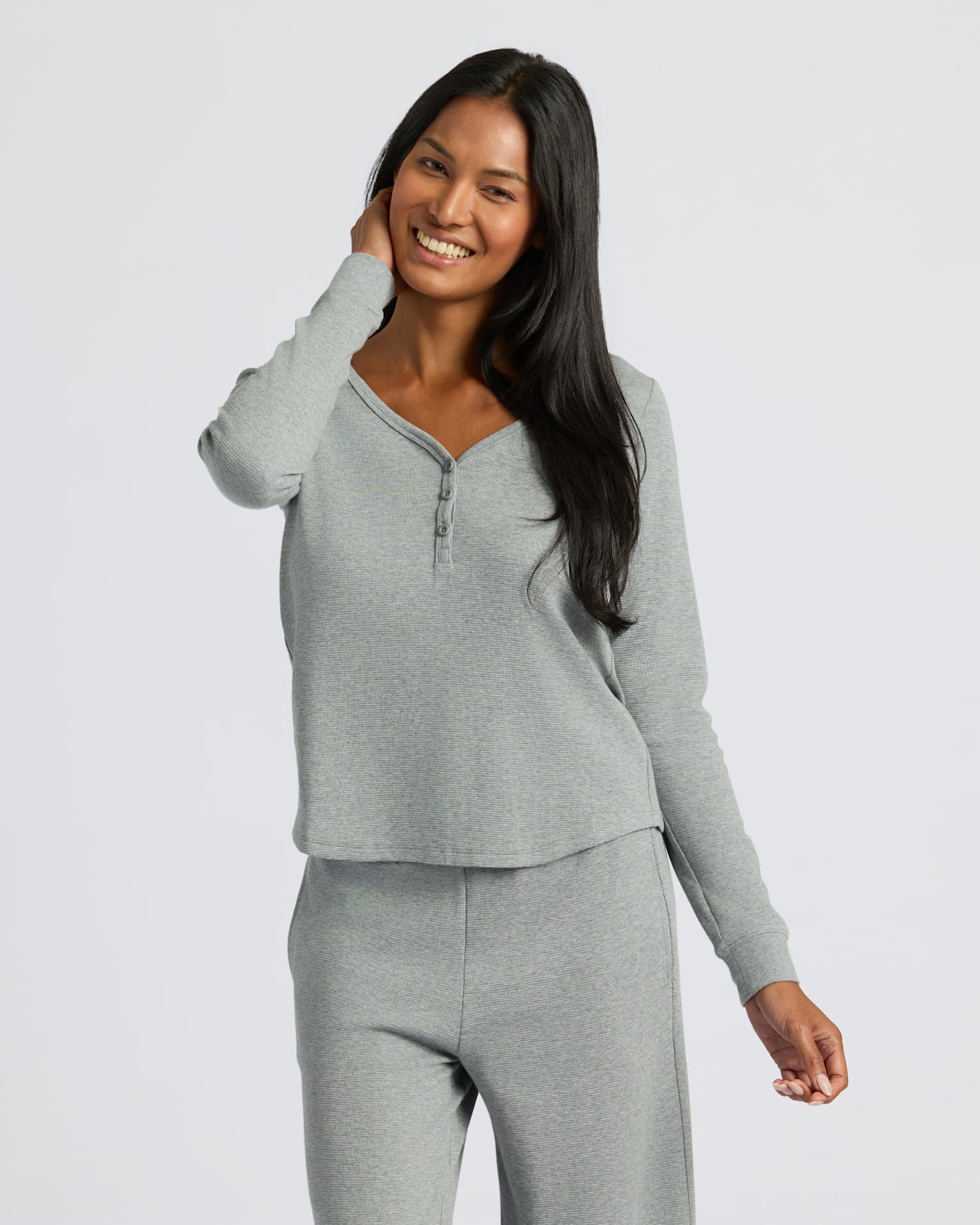 Woman wearing a gray long-sleeve top and pants on a white background