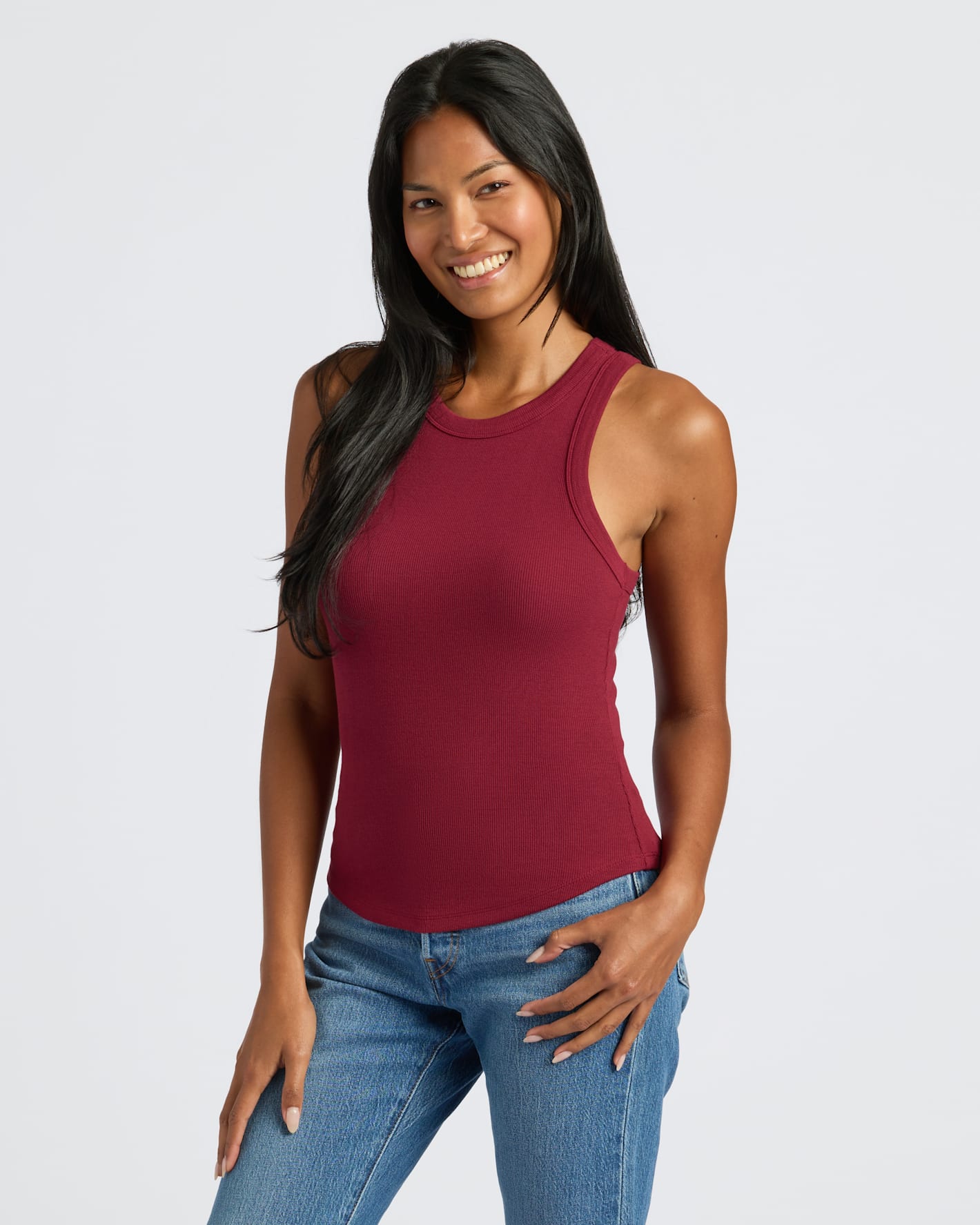 Woman in Womens Ribbed High Neck Tank, deep red, smiling confidently.