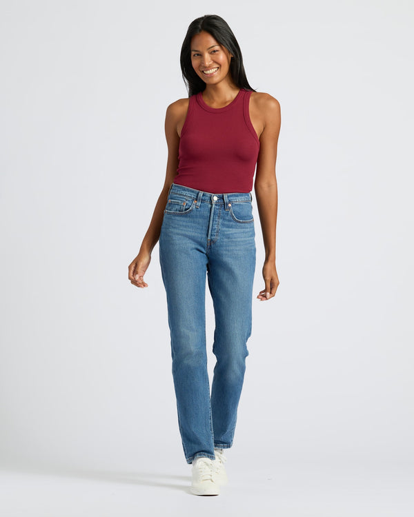 Woman in Womens Dark Maroon Ribbed High Neck Tank with jeans, smiling.
