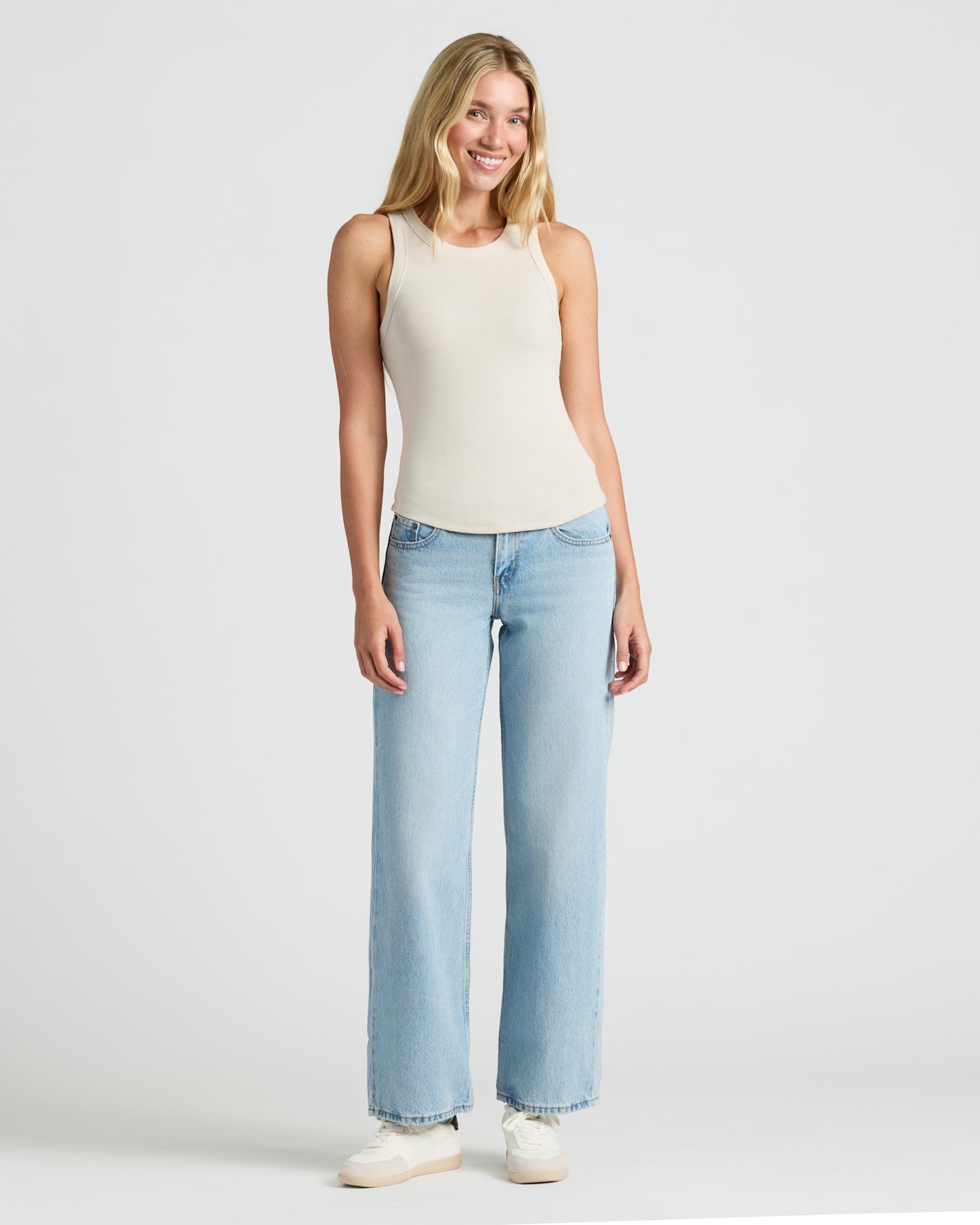Woman in Womens Ribbed High Neck Tank 3-Pack, smiling in casual jeans and sneakers.