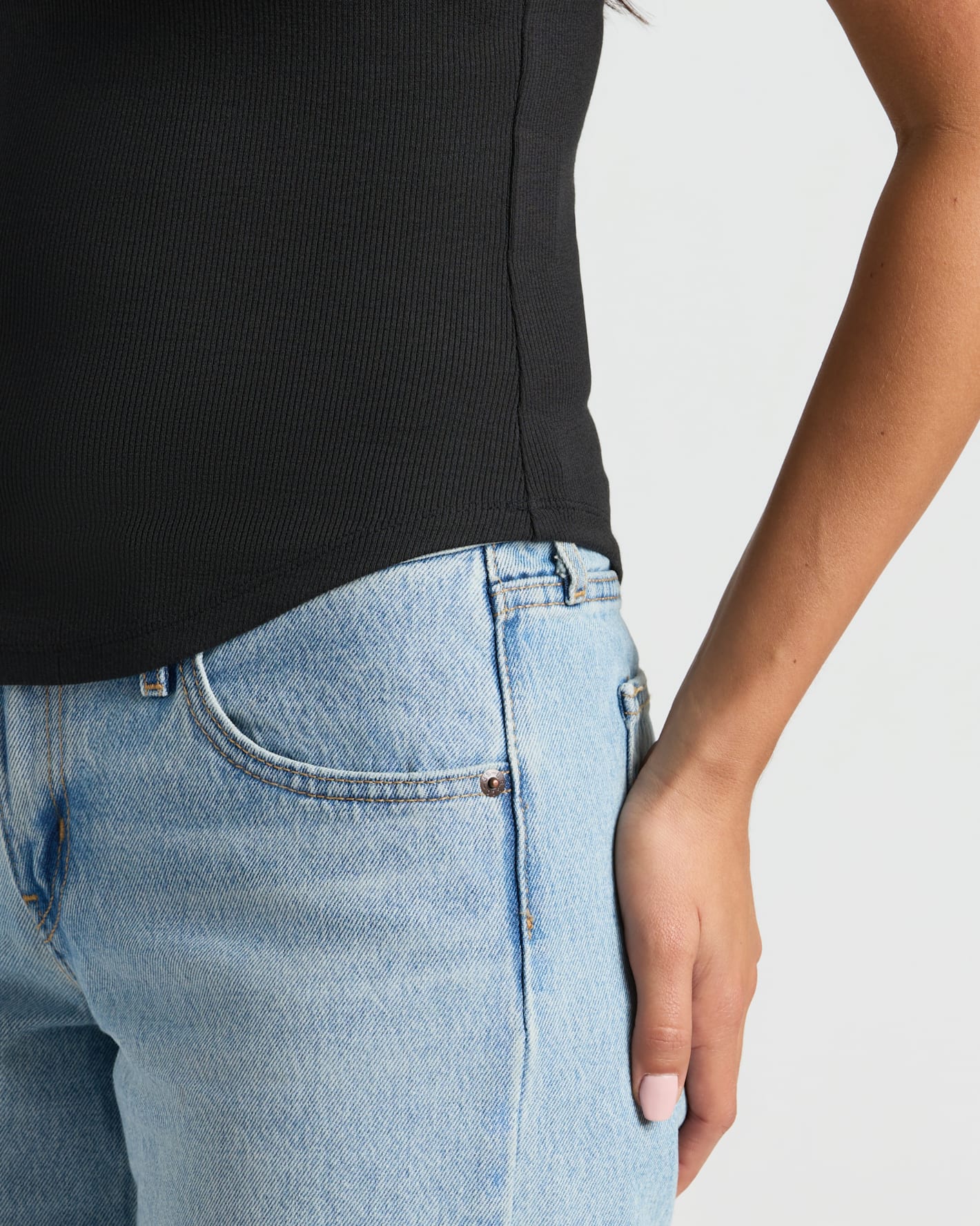 Woman wearing Womens Ribbed High Neck Tank in black, paired with jeans.