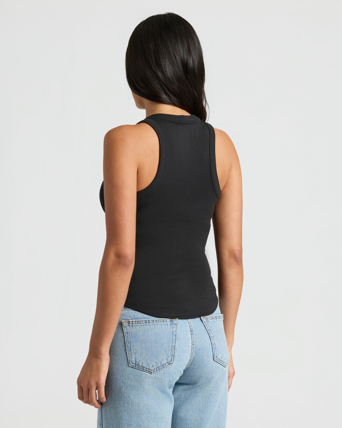 Model wearing Womens Black Ribbed High Neck Tank with light-wash jeans.