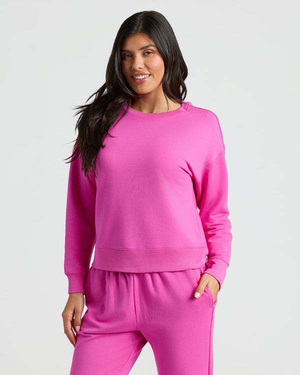 Woman wearing a pink sweatshirt and pants on a white background