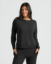 Woman wearing a black sweatshirt and pants on a light gray background