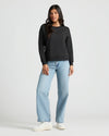Woman wearing Womens Black Slouch Pullover Crew, jeans, sneakers.