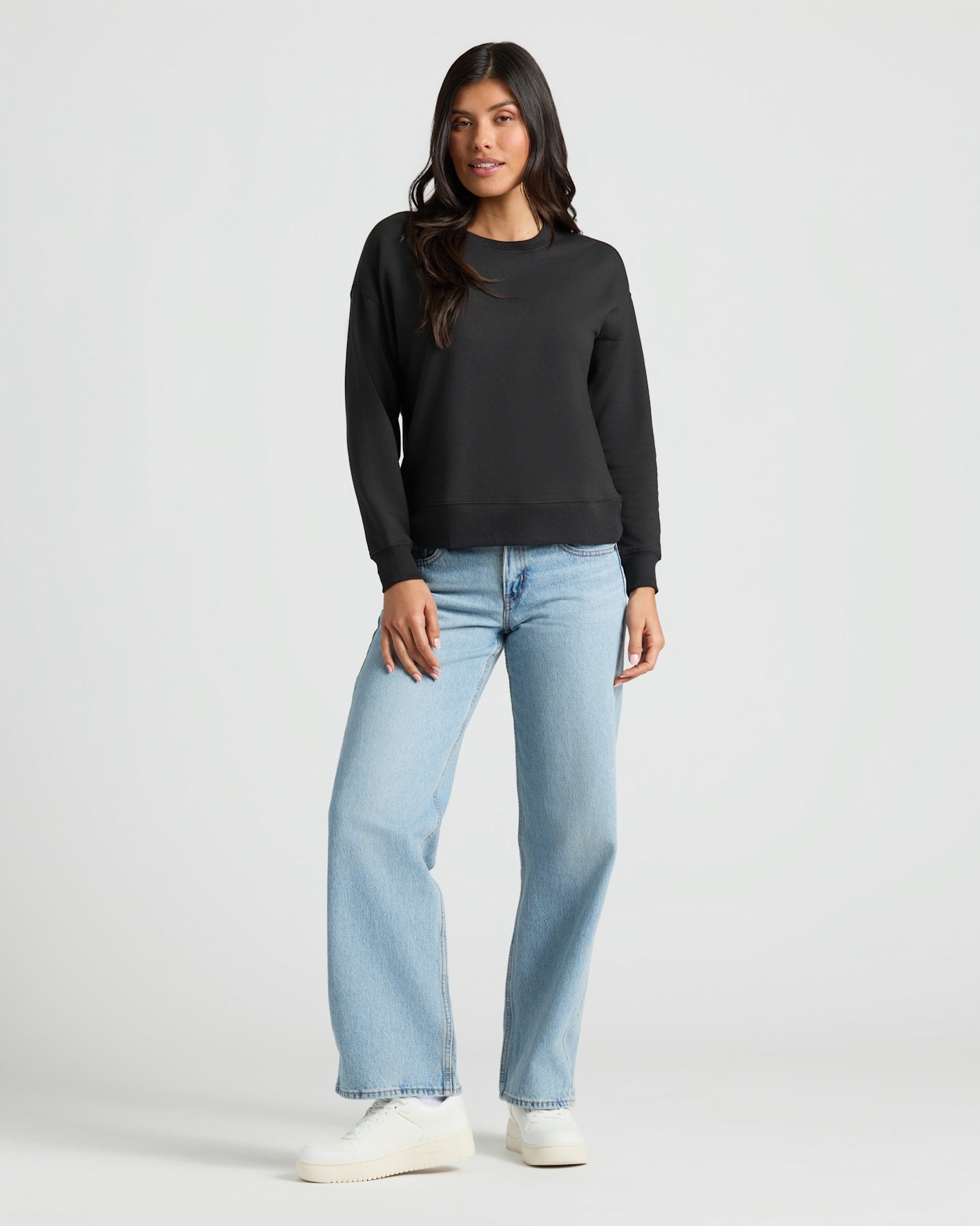 Woman wearing Womens Black Slouch Pullover Crew, jeans, sneakers.