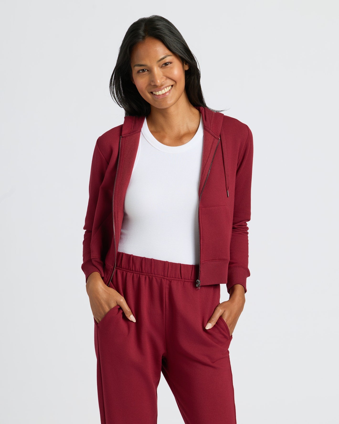 Woman wearing Womens Dark Maroon Crop Zip Hoodie, smiling, hands in pockets.