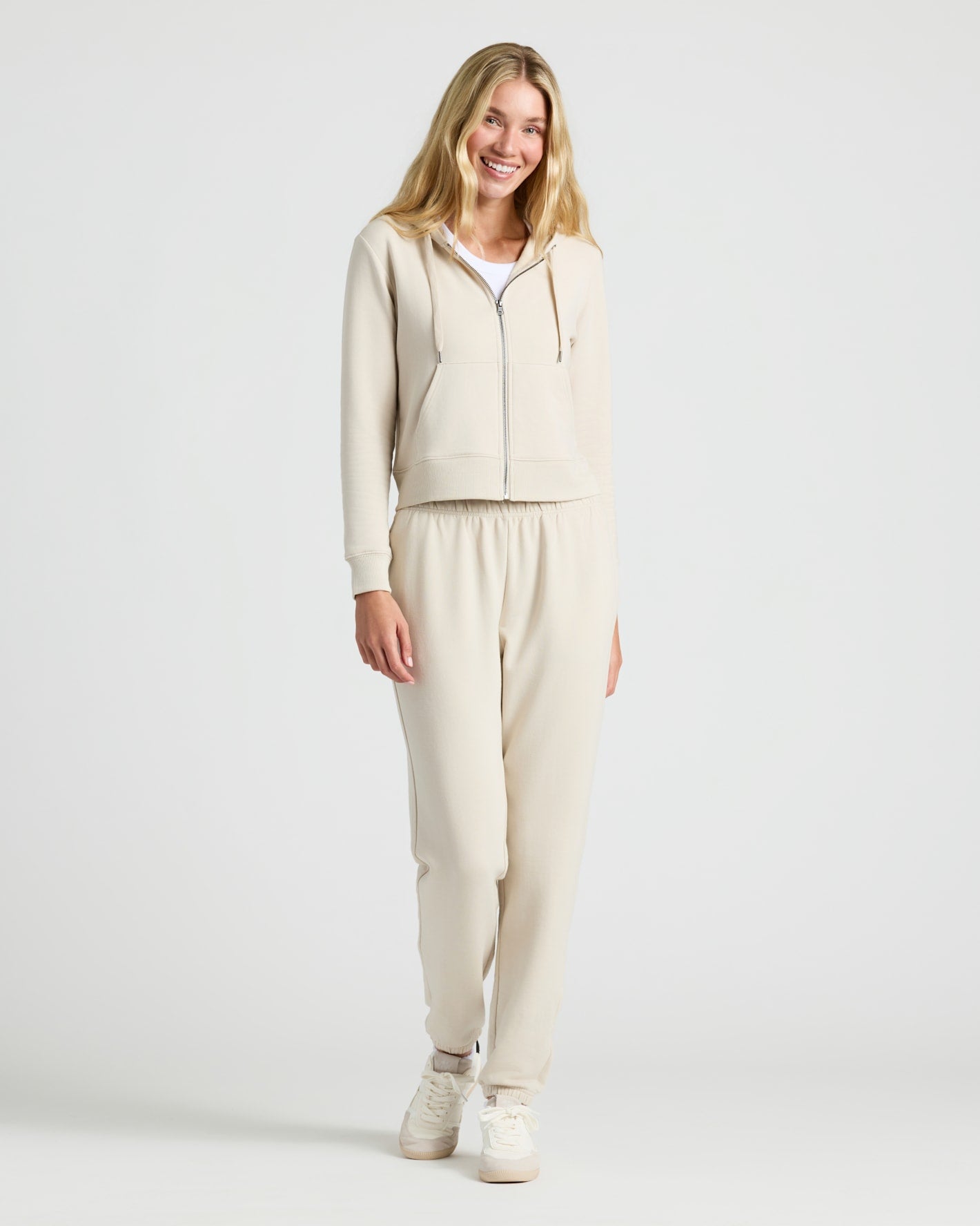 Woman in Womens Oatmeal Crop Zip Hoodie, smiling in loungewear set.