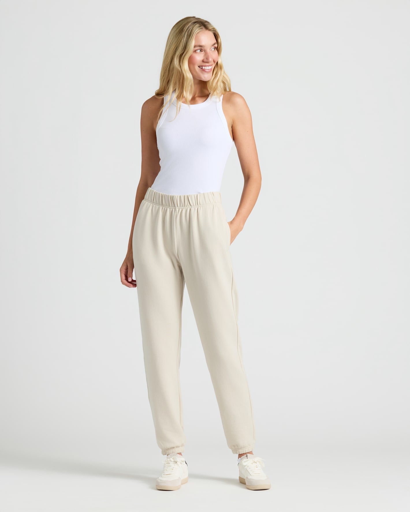 Woman models Womens Oatmeal Relaxed Joggers, paired with a white tank.
