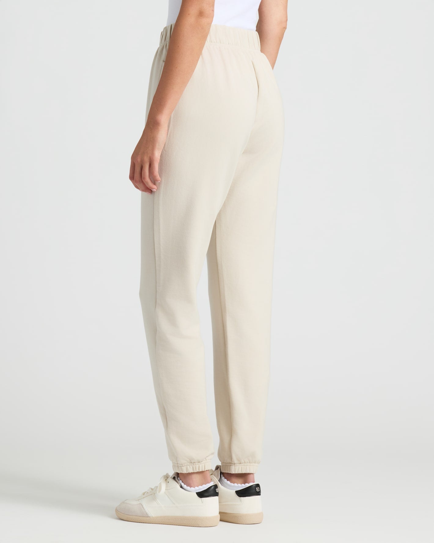 Womens Oatmeal Relaxed Joggers with elastic cuffs and white sneakers.