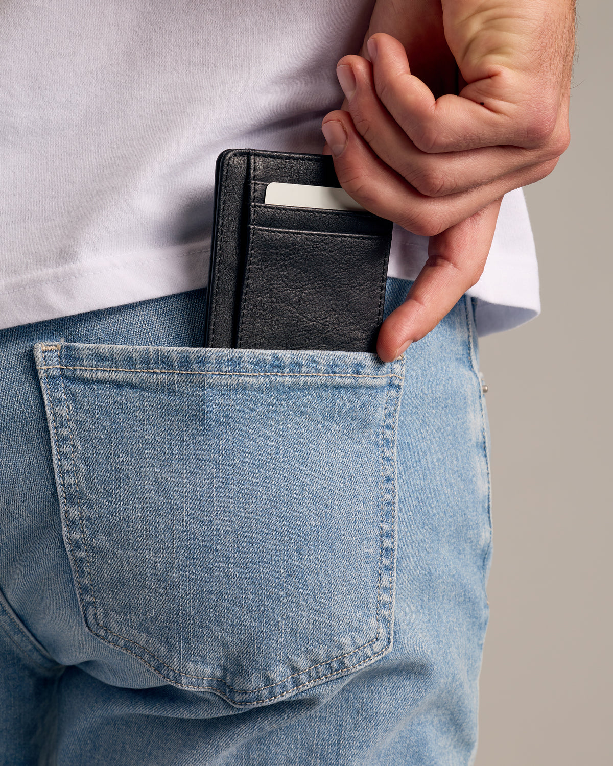 Black Classic Wallet in back pocket of light-wash jeans.