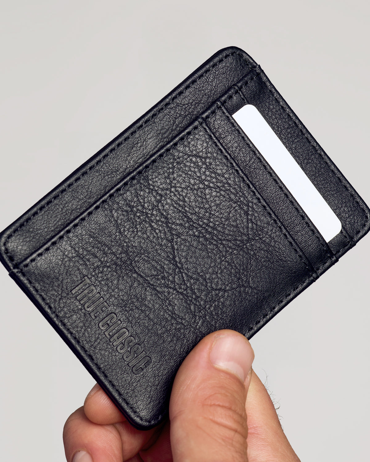 Black Classic Wallet in hand, showcasing pebbled vegan leather and card slot.