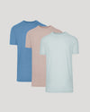 Three plain t-shirts in blue, pink, and light blue on a gray background