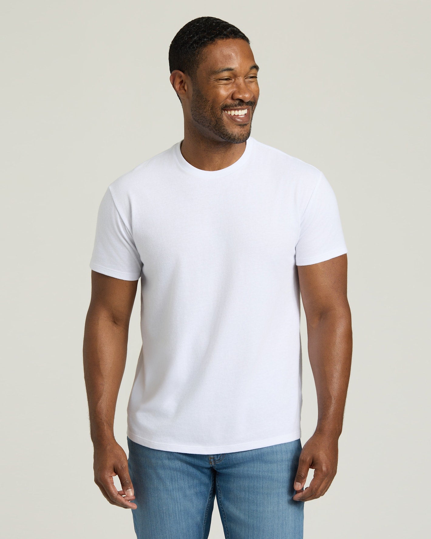Man wearing a plain white t-shirt and blue jeans against a light background