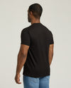 Man wearing a black t-shirt and blue jeans on a light gray background