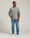 Man wearing a gray t-shirt and blue jeans standing against a plain background. MODEL_INFO: Model is 5'8" wearing size M short