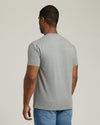 Man wearing a gray t-shirt and blue jeans on a plain background