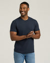 Man wearing a navy blue t-shirt and light blue jeans against a plain background