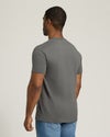 Man wearing a gray t-shirt and blue jeans on a plain background