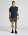 Man wearing a navy t-shirt and gray shorts on a white background