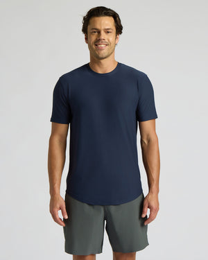 Man wearing a navy blue t-shirt and gray shorts on a light gray background