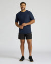 Man wearing a navy t-shirt and black shorts on a light gray background