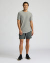 A man modeling a light gray short-sleeve crewneck t-shirt and dark gray athletic shorts, standing against a light gray studio background.