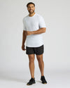 Man wearing a white t-shirt and black shorts on a light gray background