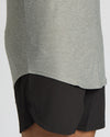 Close-up of a person wearing a heather gray athletic top and black athletic shorts against a light gray background.