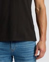 Person wearing a black t-shirt and blue jeans on a plain background