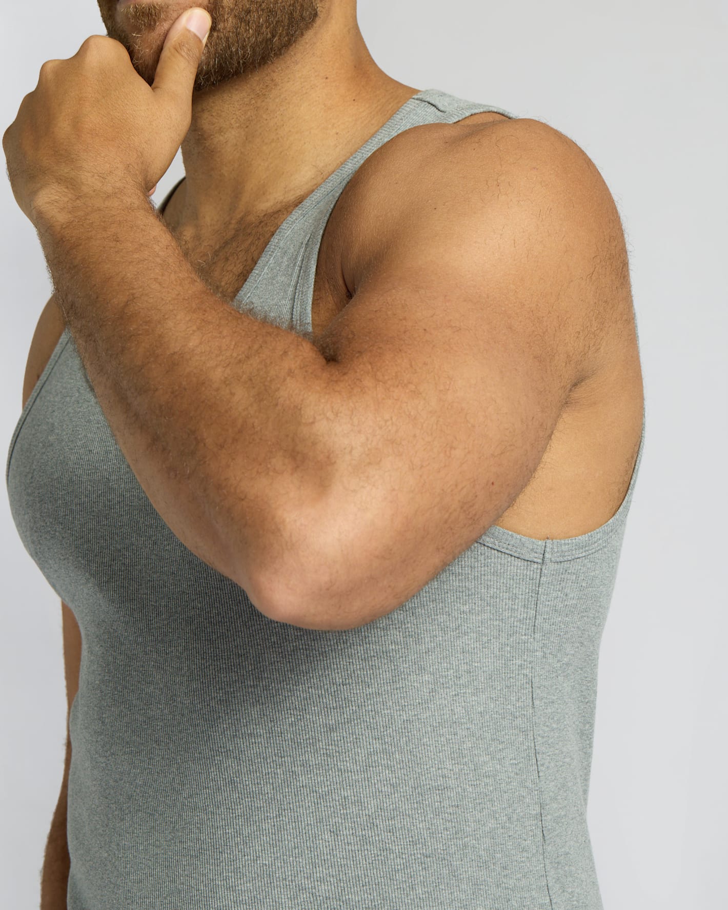 Person wearing a gray tank top on a plain background
