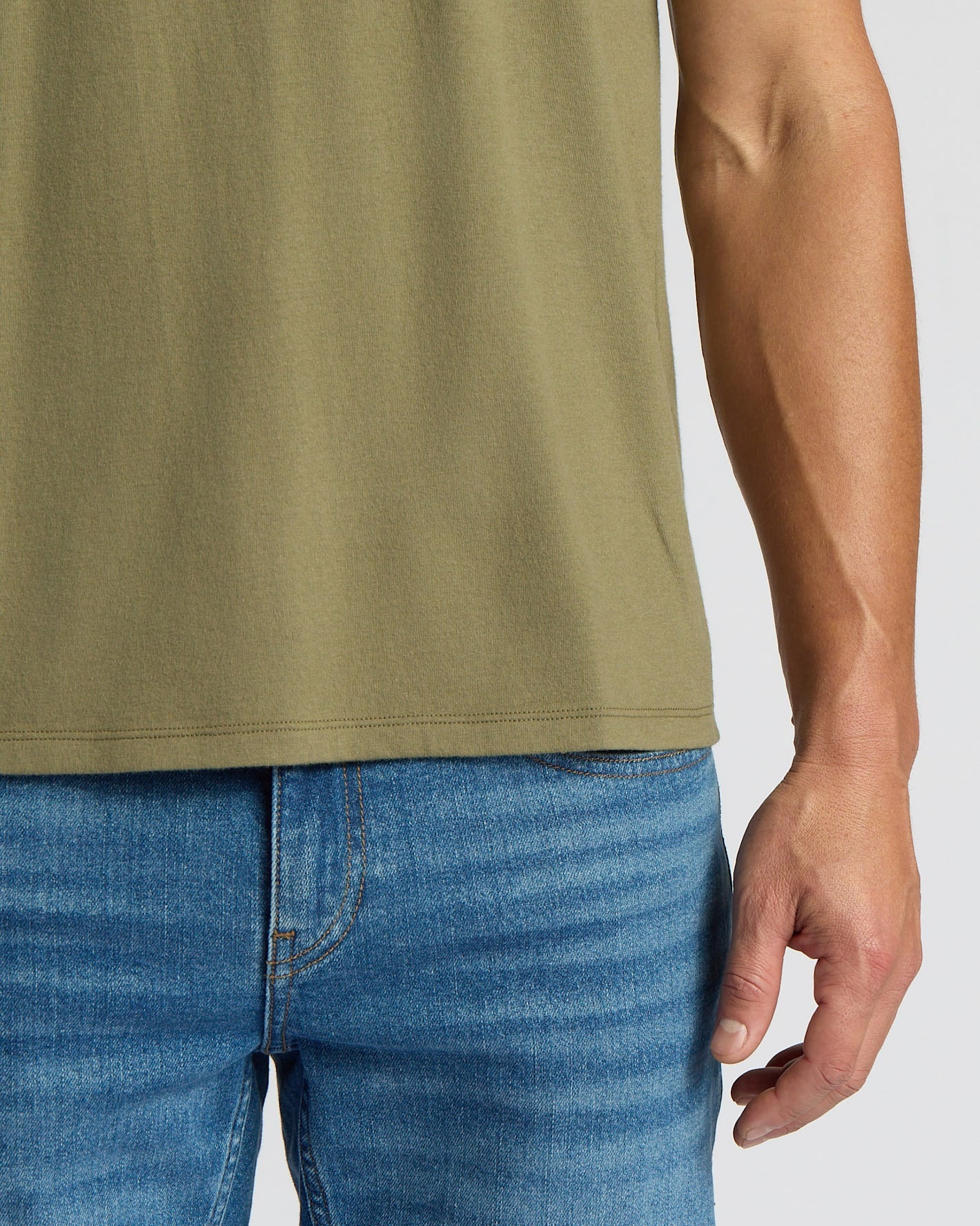 Person wearing a green sleeveless shirt and blue jeans on a white background