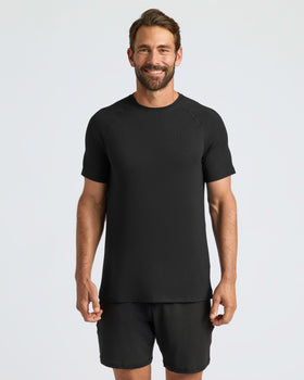Man wearing Black Active Mesh Crew, stands relaxed, showcasing athletic fit.