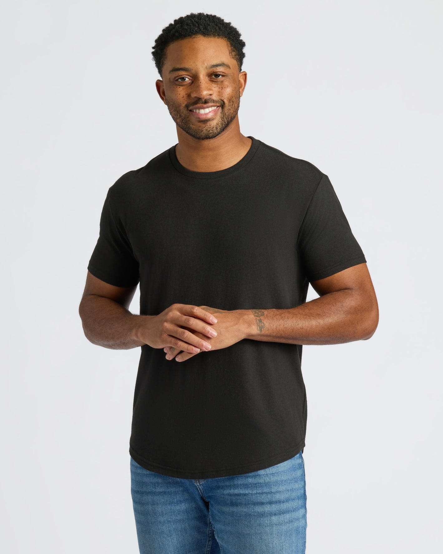 Man modeling All Black Curved Hem Classic Crew Neck, showcasing fit and design.