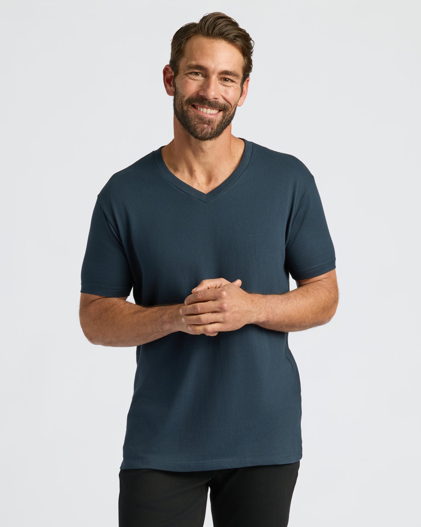 Man in Classic V-Neck 10-Pack T-shirt, hands clasped, smiling.