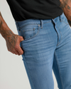 Close-up of a man wearing Medium Indigo Wash Slim Comfort Stretch Jeans, showing a fitted silhouette and soft stretch fabric for comfort.