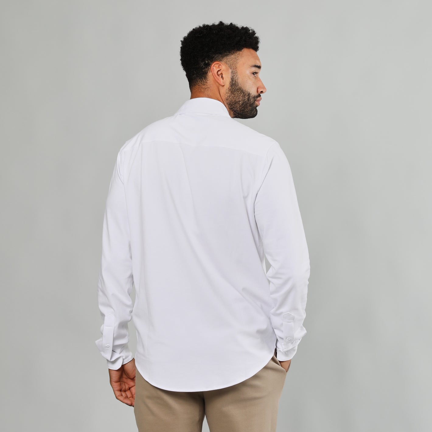 White Button Up Shirt on man, back view, neutral backdrop.