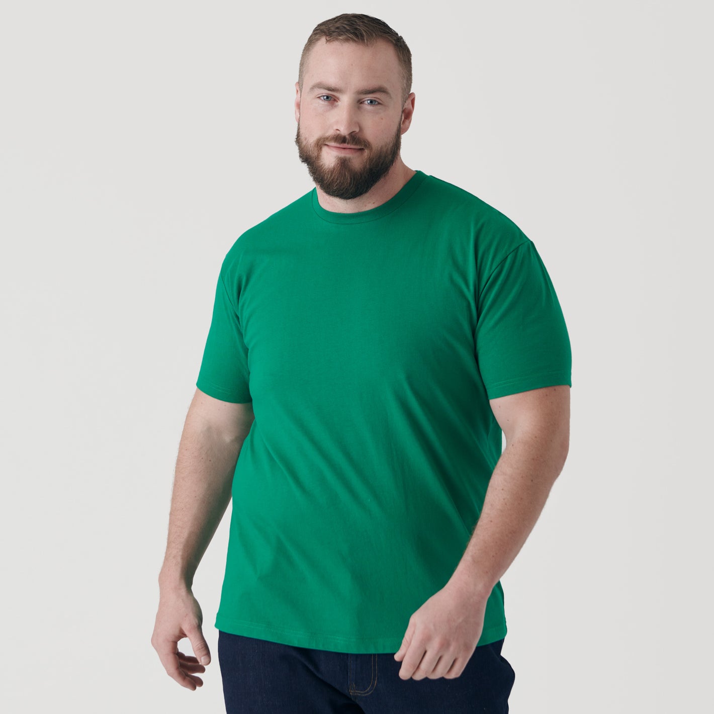Man wearing Kelly Green Short Sleeve Crew Neck Tee and dark pants.