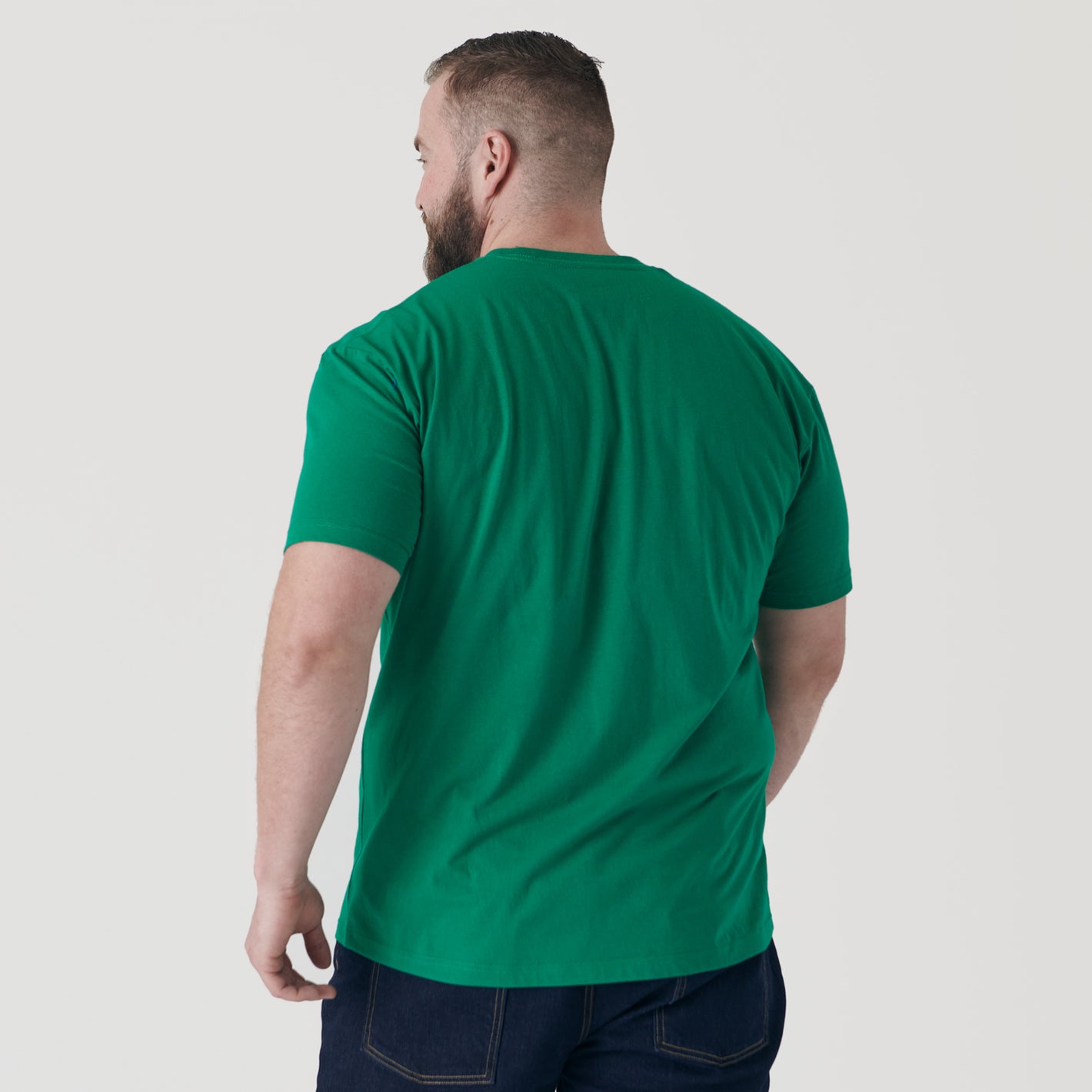 Man wearing Kelly Green Short Sleeve Crew Neck Tee and dark jeans.