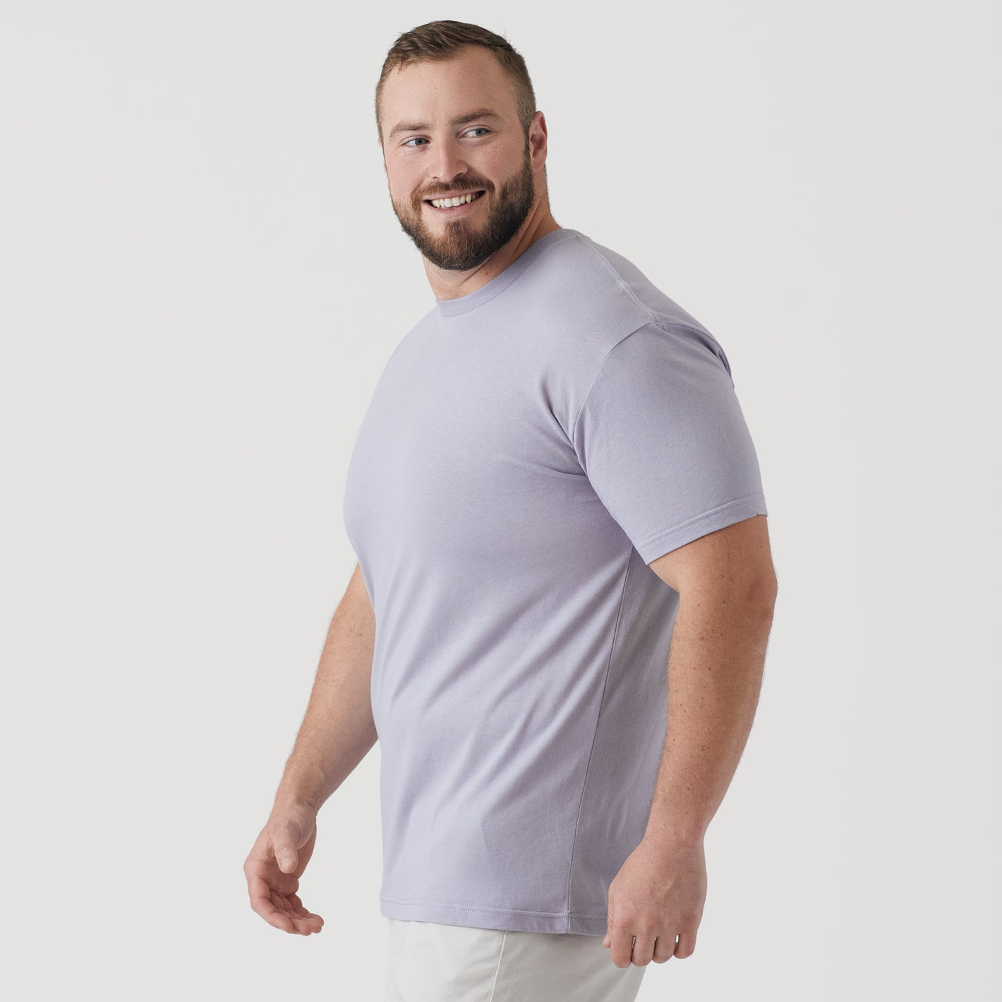 Man wearing Lilac Gray Short Sleeve Crew Neck Tee, smiling slightly off-camera.