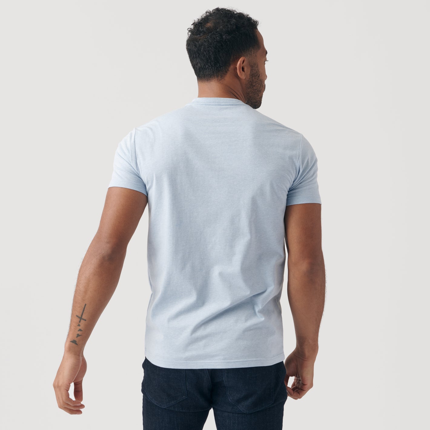 Man wearing Heather Pale Blue Short Sleeve Crew Neck Tee and dark jeans.