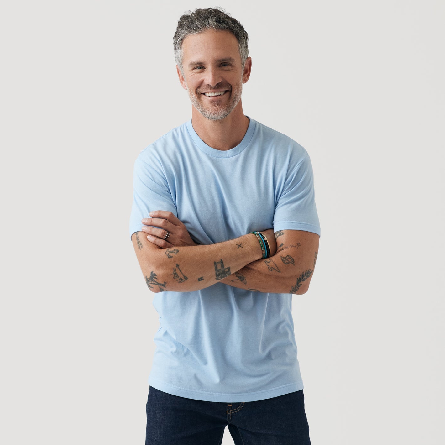 Man in Oxford Blue Short Sleeve Crew Neck Tee with tattoos.