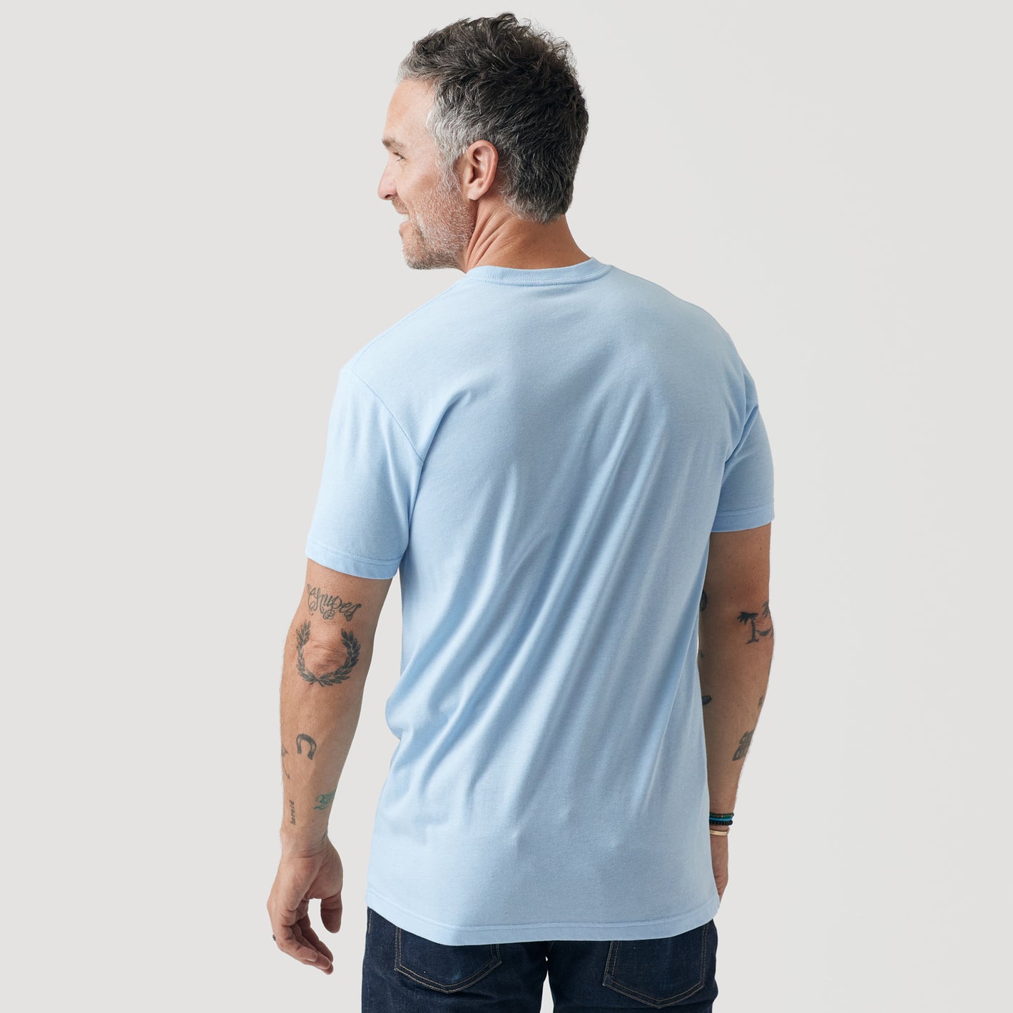 Man wearing Oxford Blue Short Sleeve Crew Neck Tee, showcasing tattoos.
